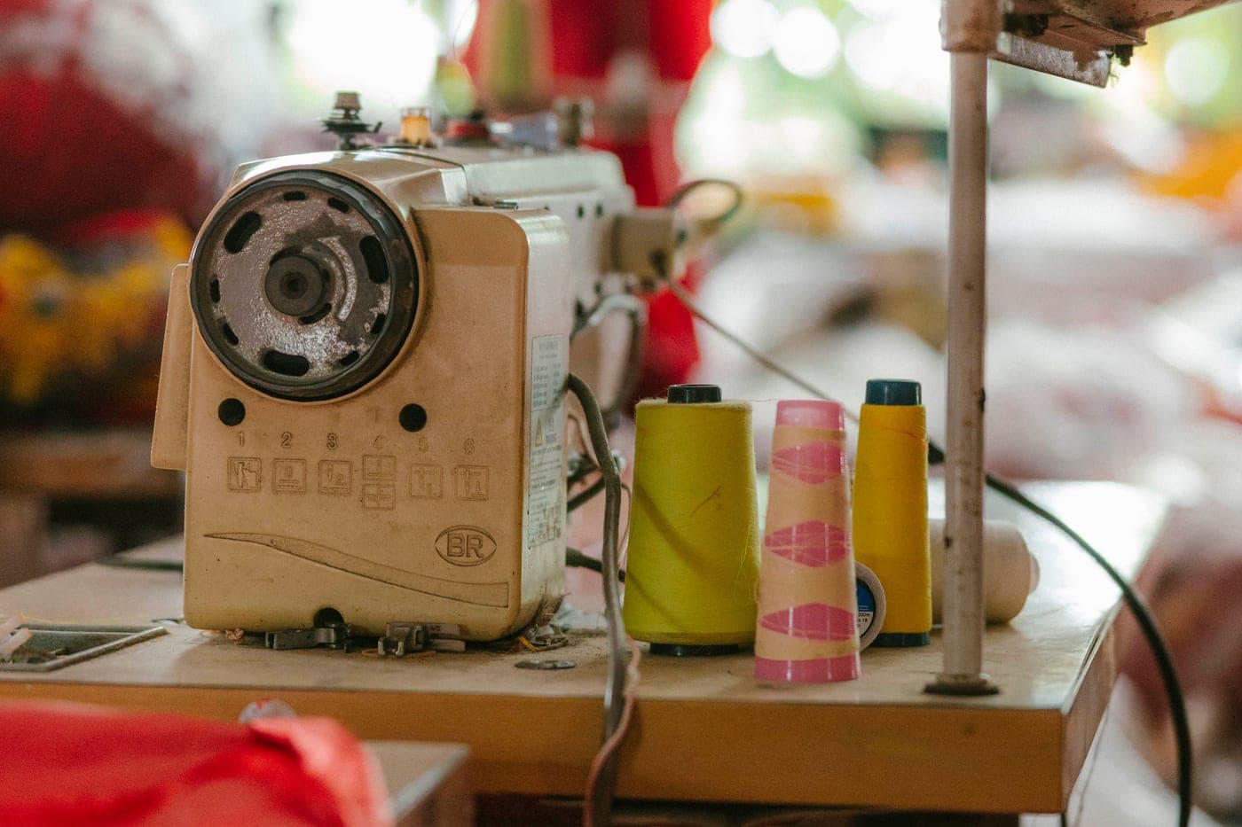 A sewing machine beside colorful spools of thread on a workshop table