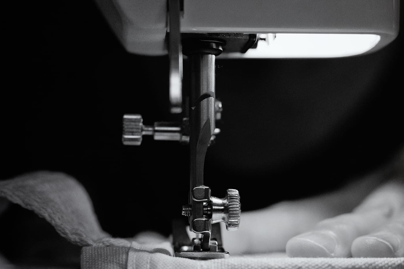 Grayscale close view of a sewing machine needle stitching fabric