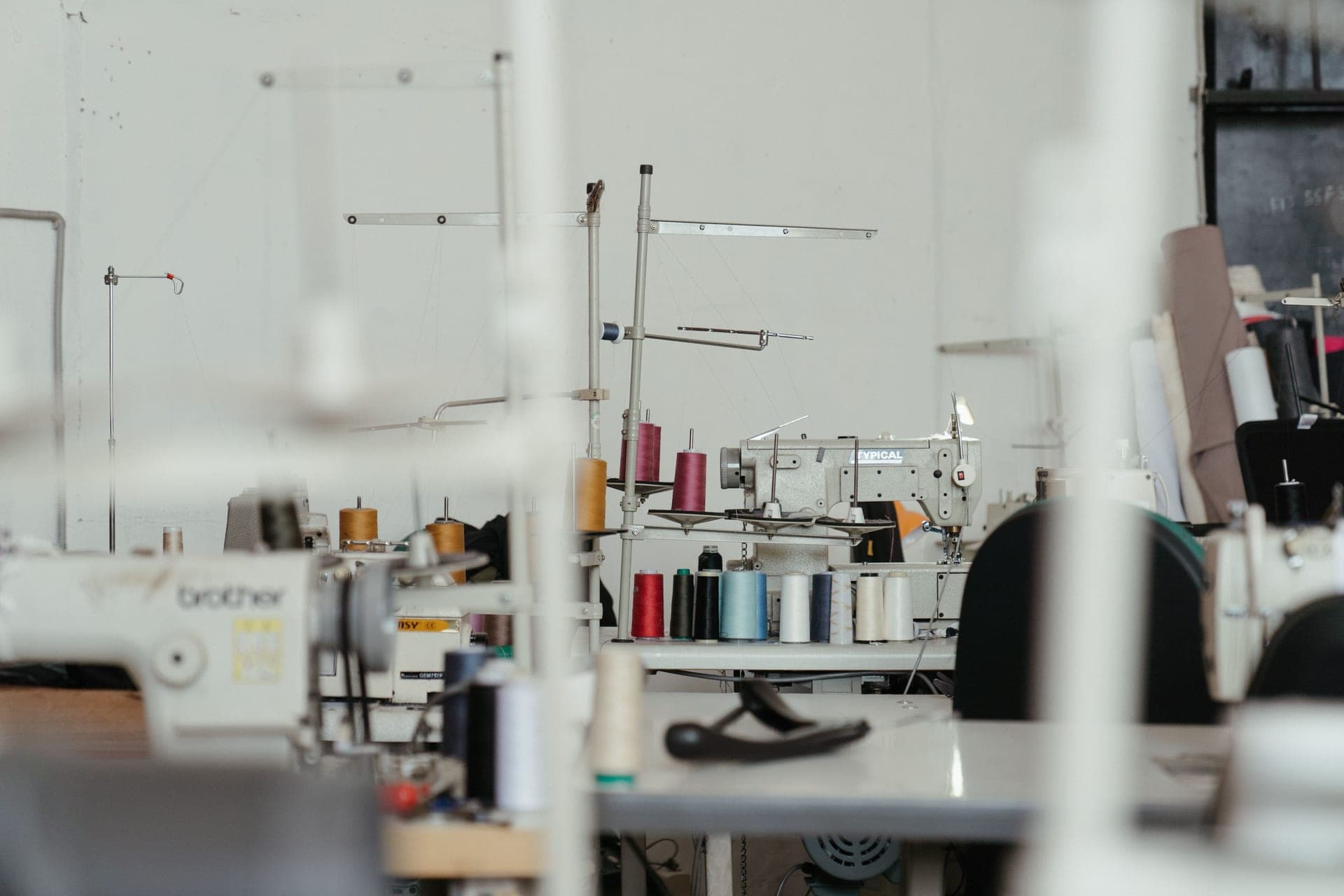 A workshop with several sewing machines and spools of thread