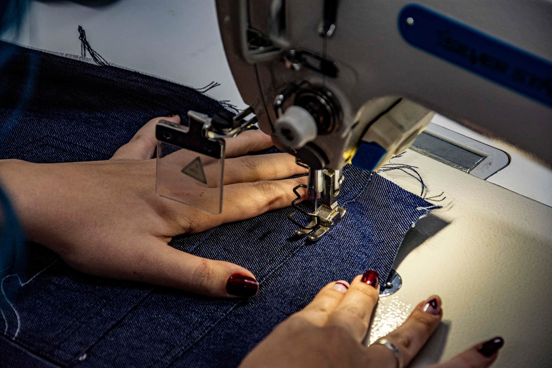 Close view of denim being stitched on a sewing machine