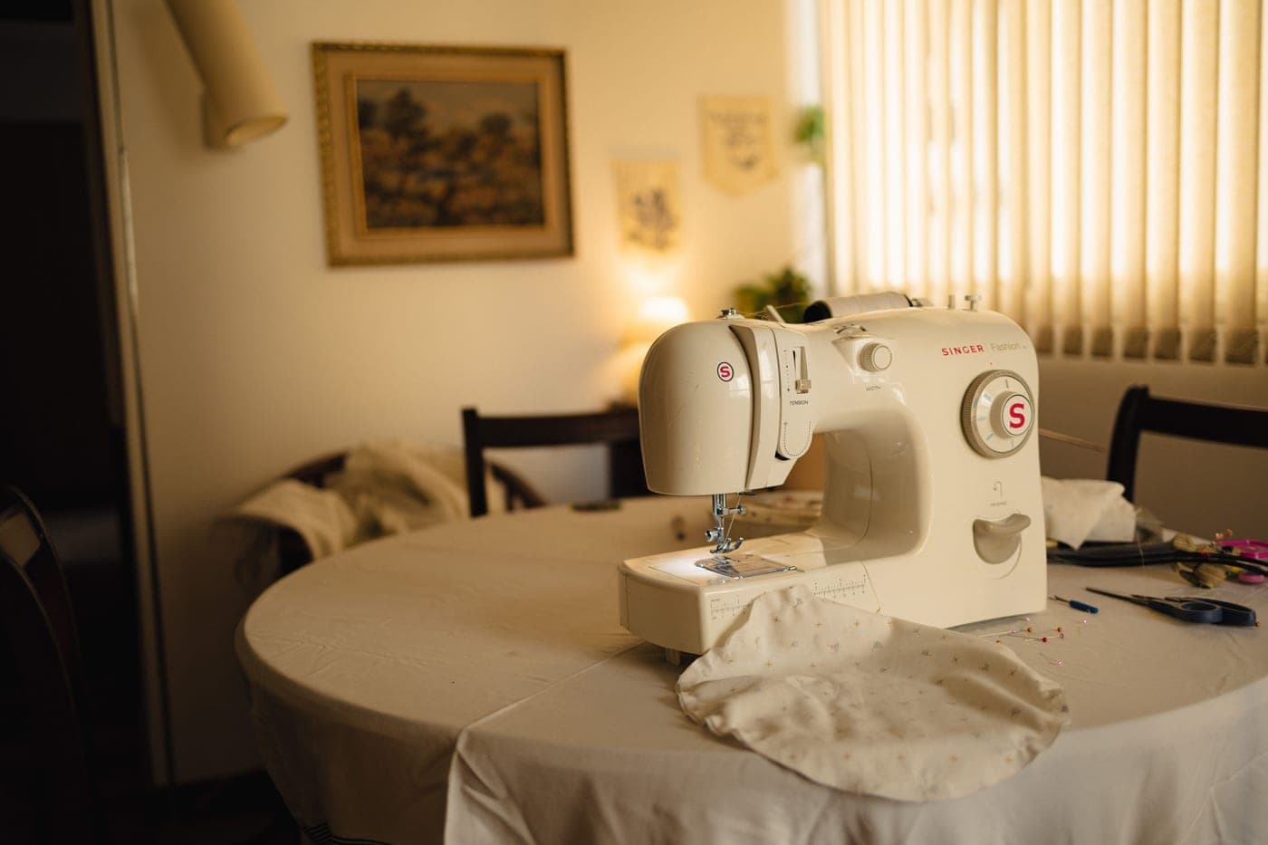 A sewing room with a machine, fabric and tools on the table