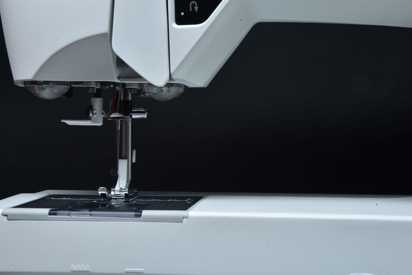 Close view of a sewing machine needle above the needle plate