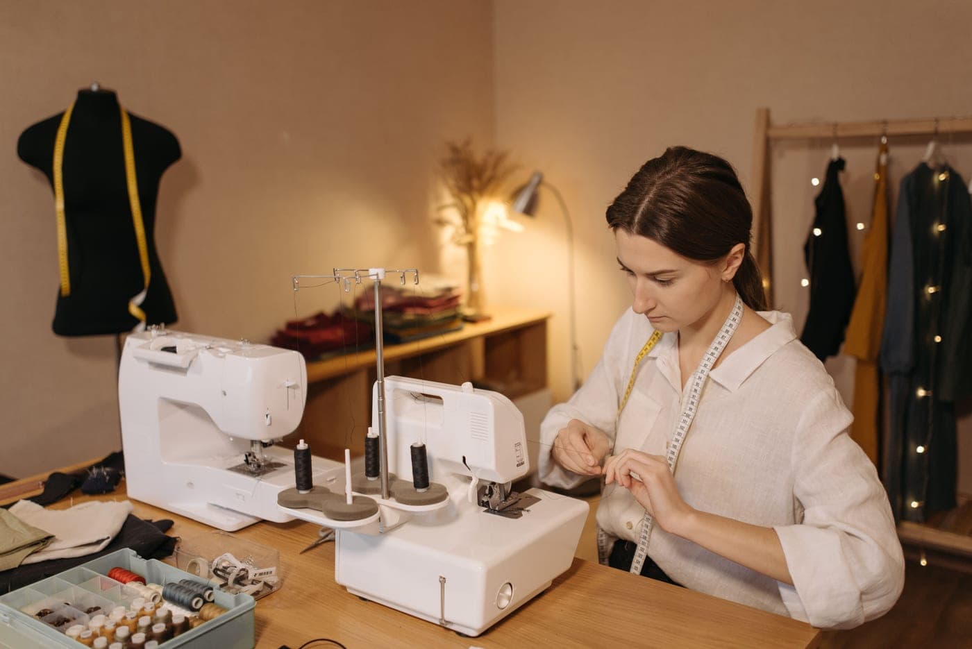 A person threading a sewing machine at a workshop bench