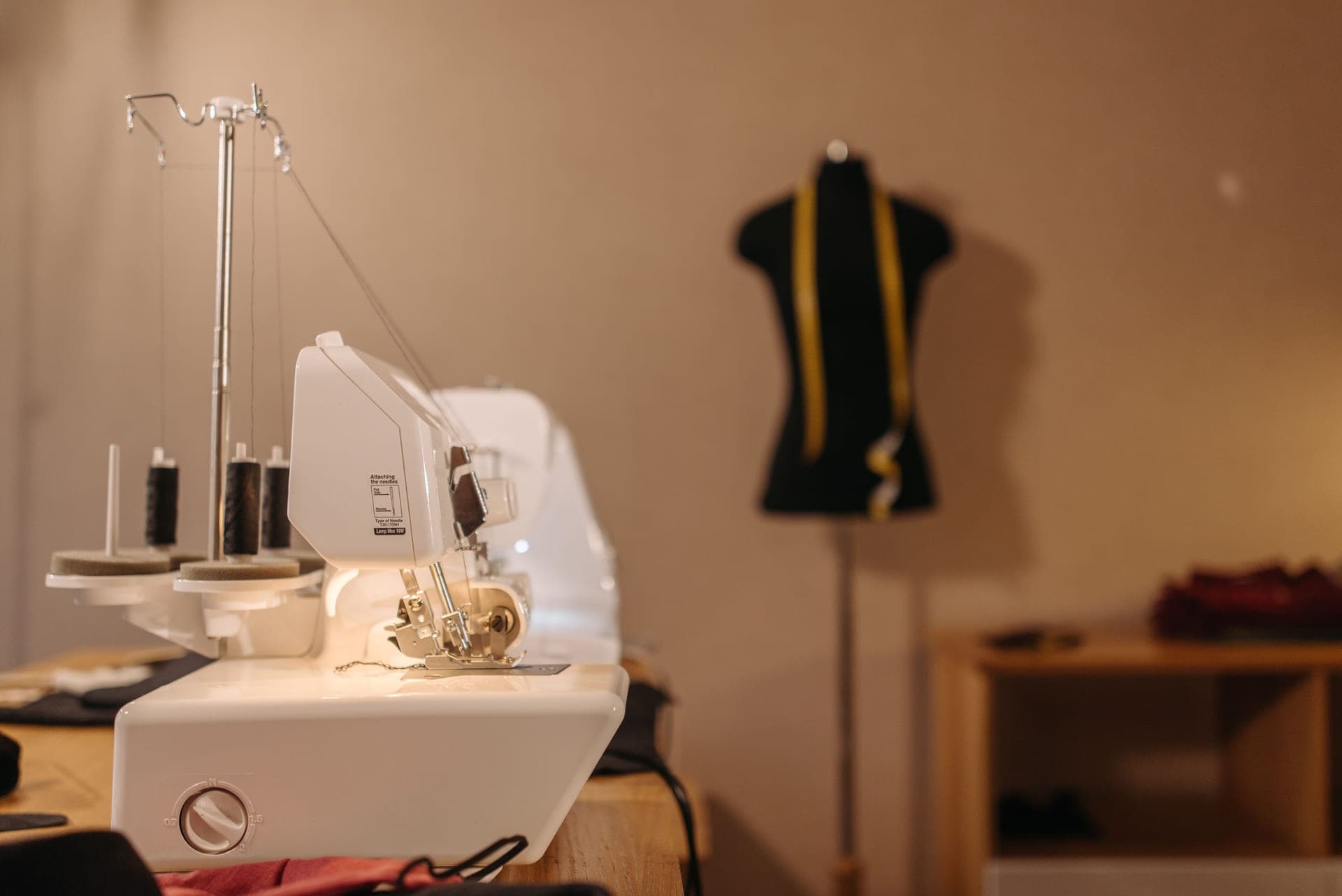 A sewing machine and a tailor's dress form in a tidy studio