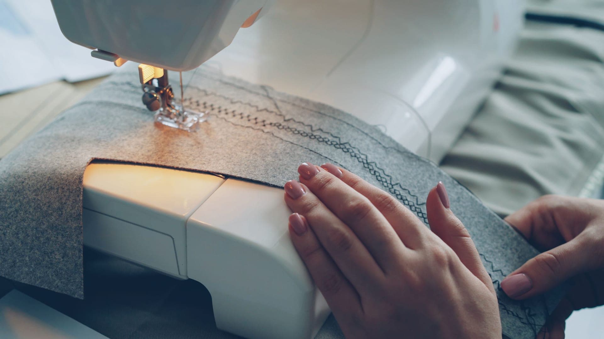 Hands guiding fabric through a sewing machine
