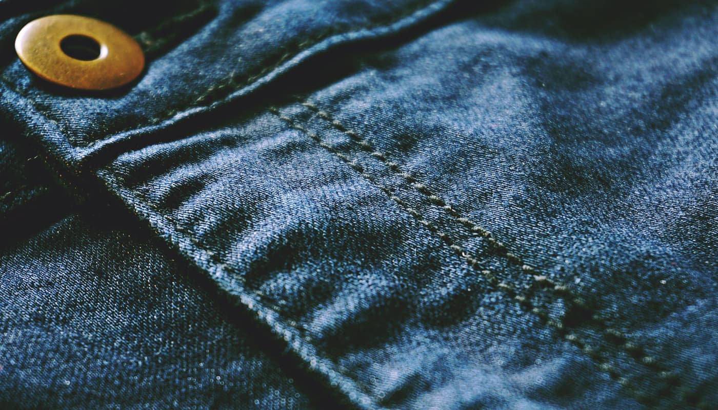 Close view of blue denim fabric showing stitching and texture
