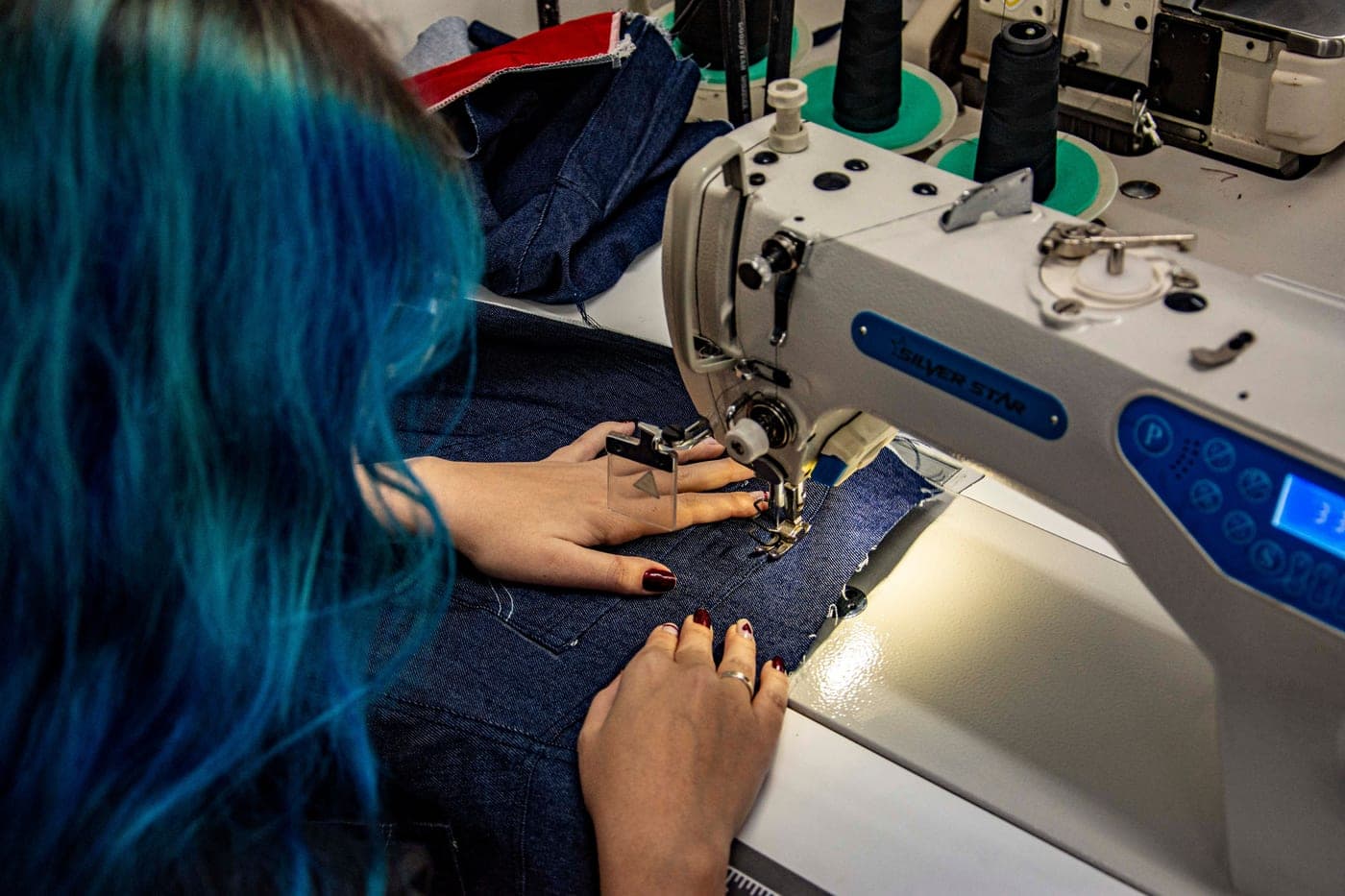 Denim fabric being sewn on a machine in a workshop