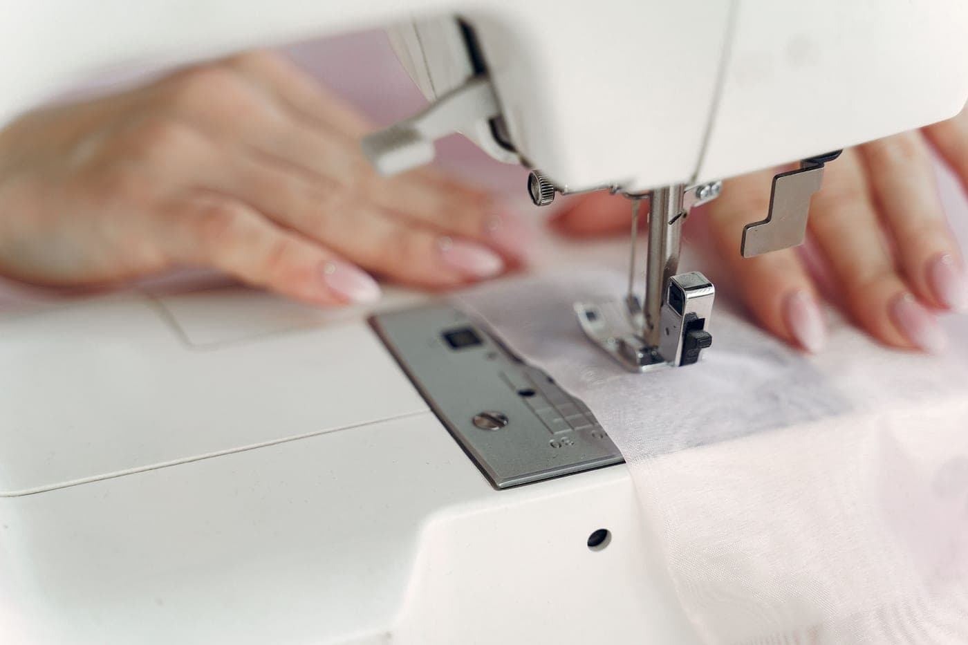 A person sewing a garment on a white sewing machine