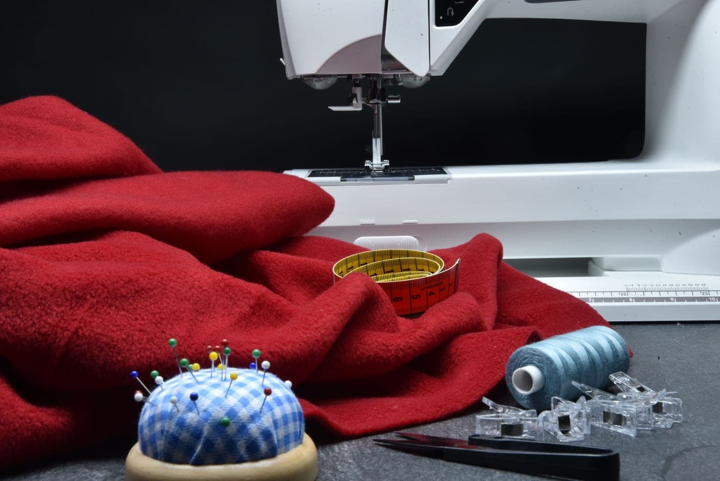 A sewing machine with red fabric and hand tools beside it