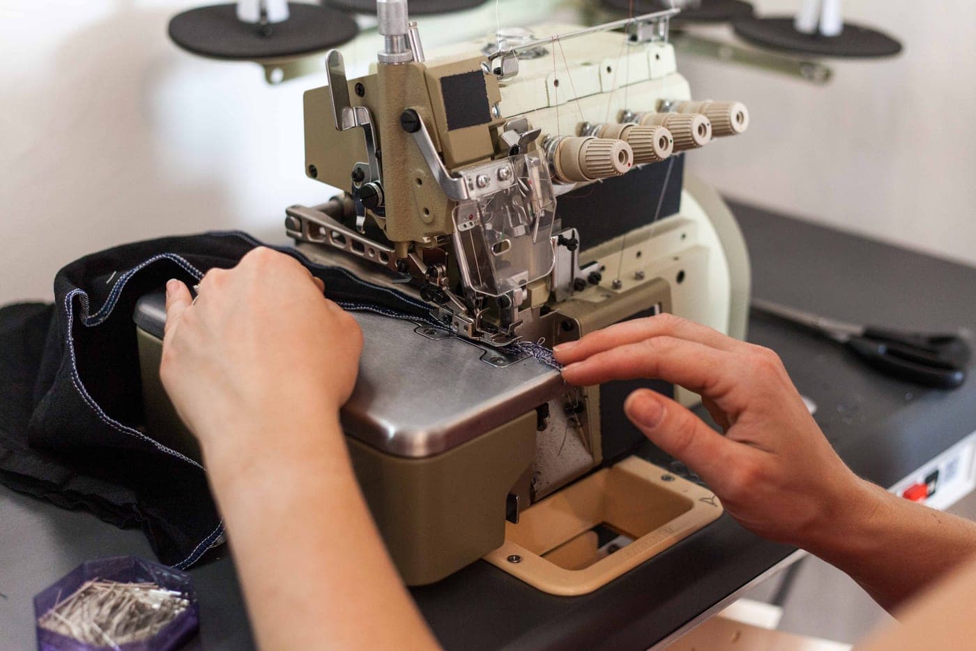 A person guiding a garment through a sewing machine