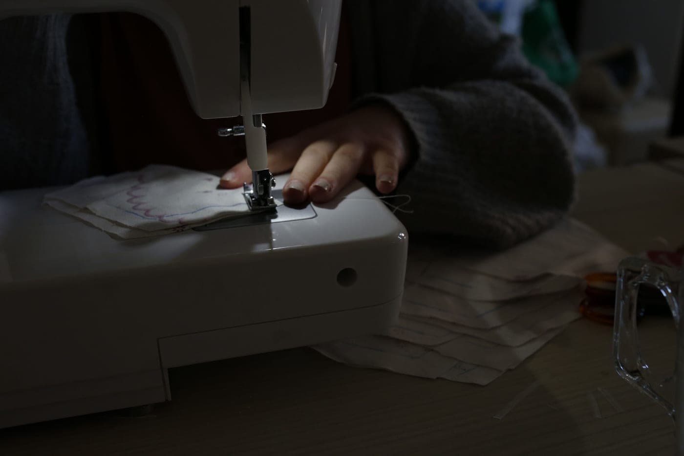A person sewing at a machine with fabric spread across the bed