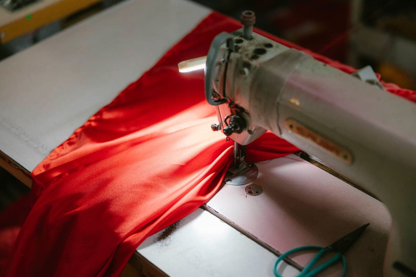 A sewing machine stitching a length of red fabric