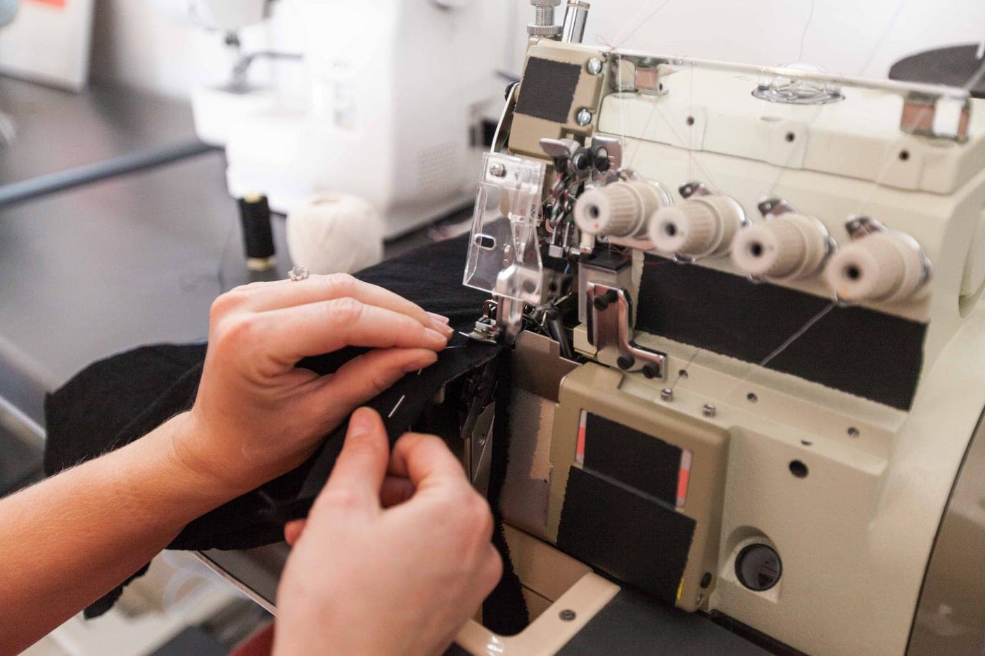 Close view of a person feeding fabric through a sewing machine