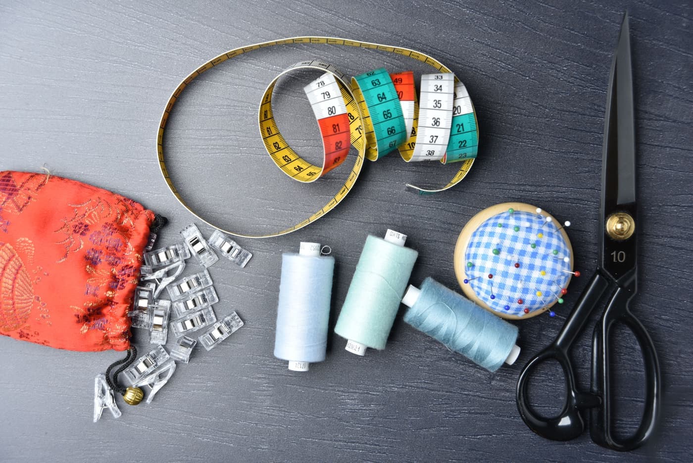 Colorful sewing supplies arranged on a dark surface