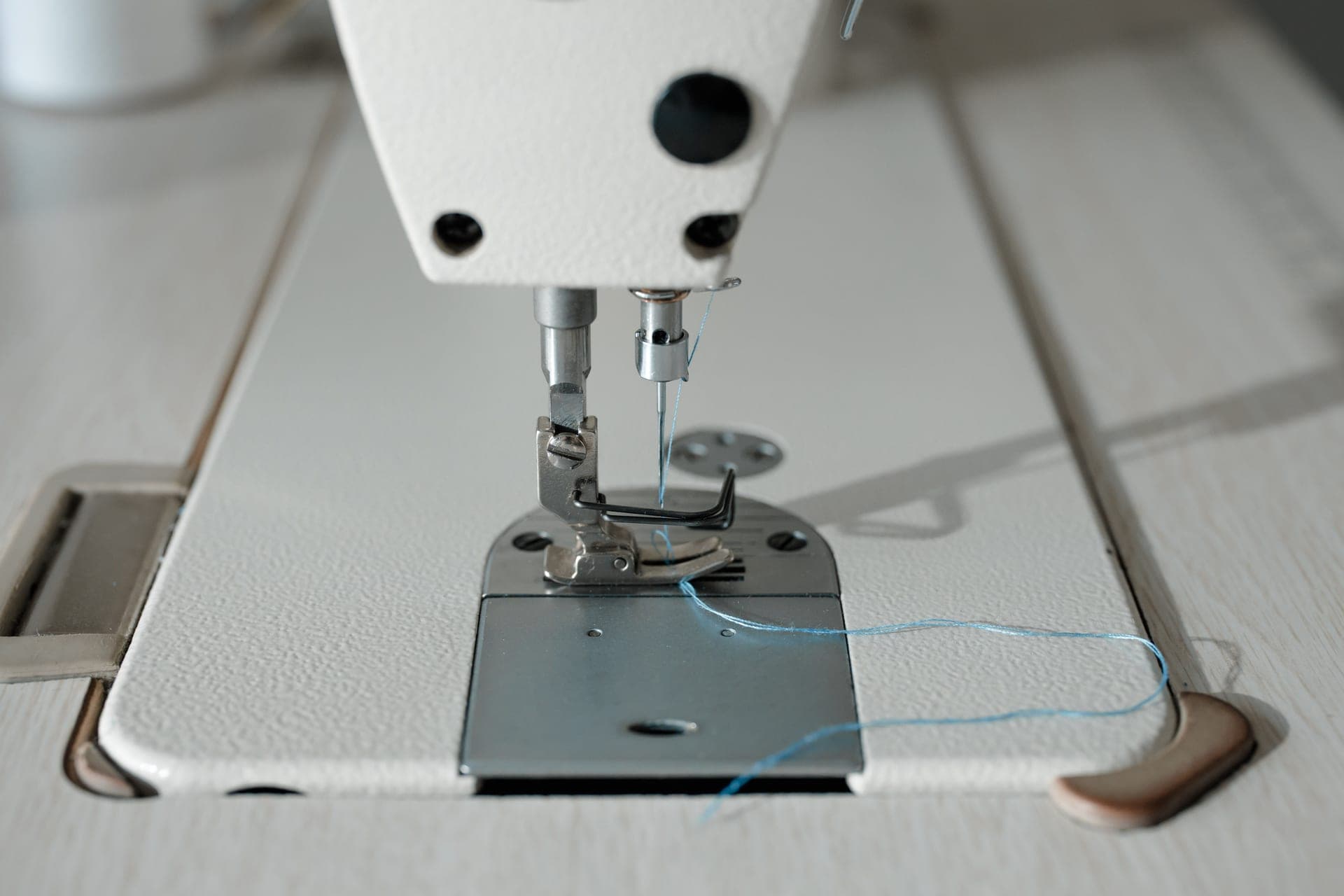 Close view of a sewing machine needle with blue thread