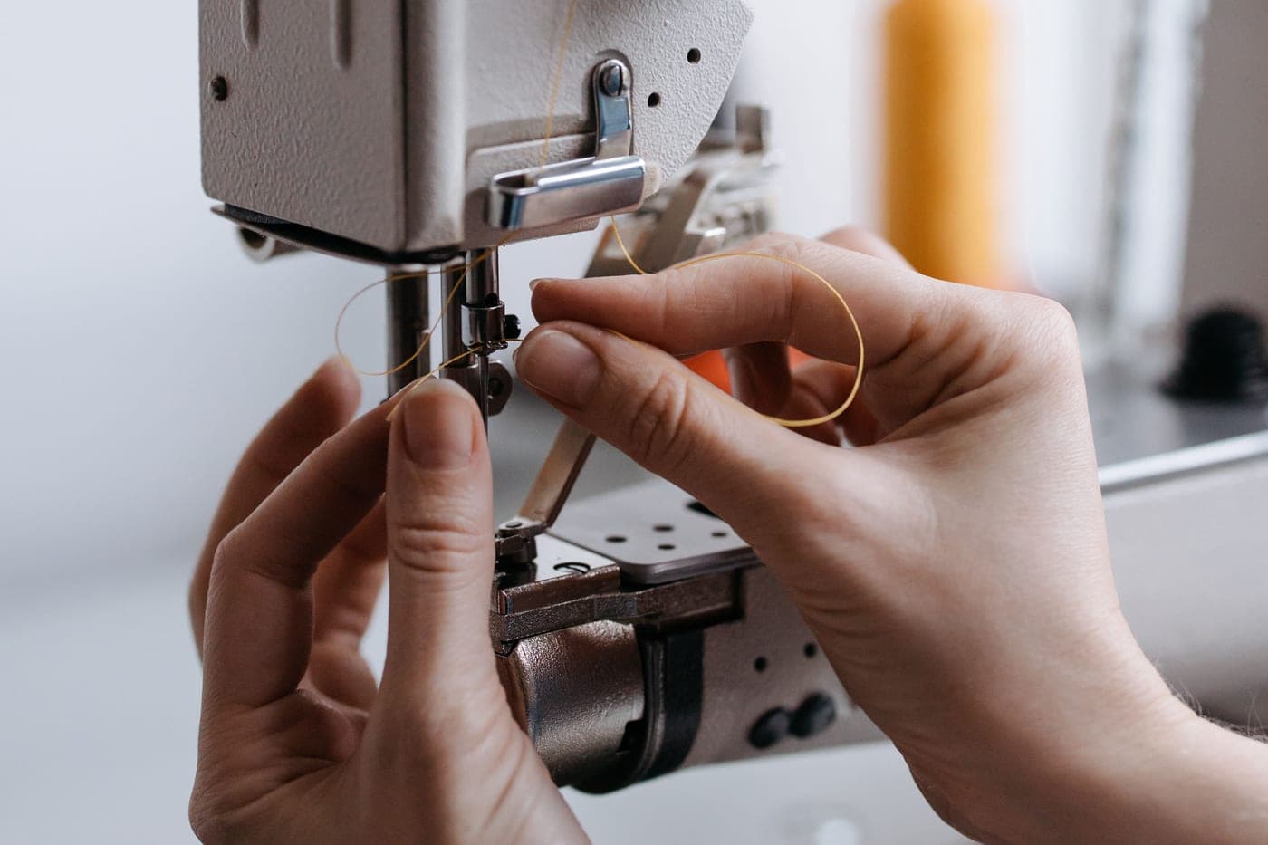 Hands threading the needle of a sewing machine