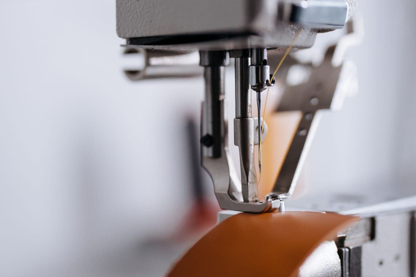 Leather being fed under a sewing machine presser foot