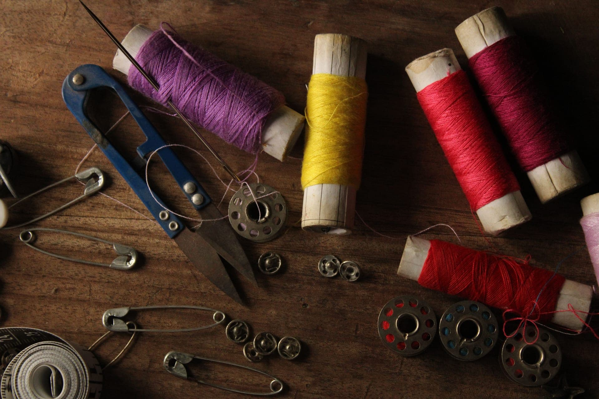 Colorful thread spools and sewing tools laid out on a wooden table
